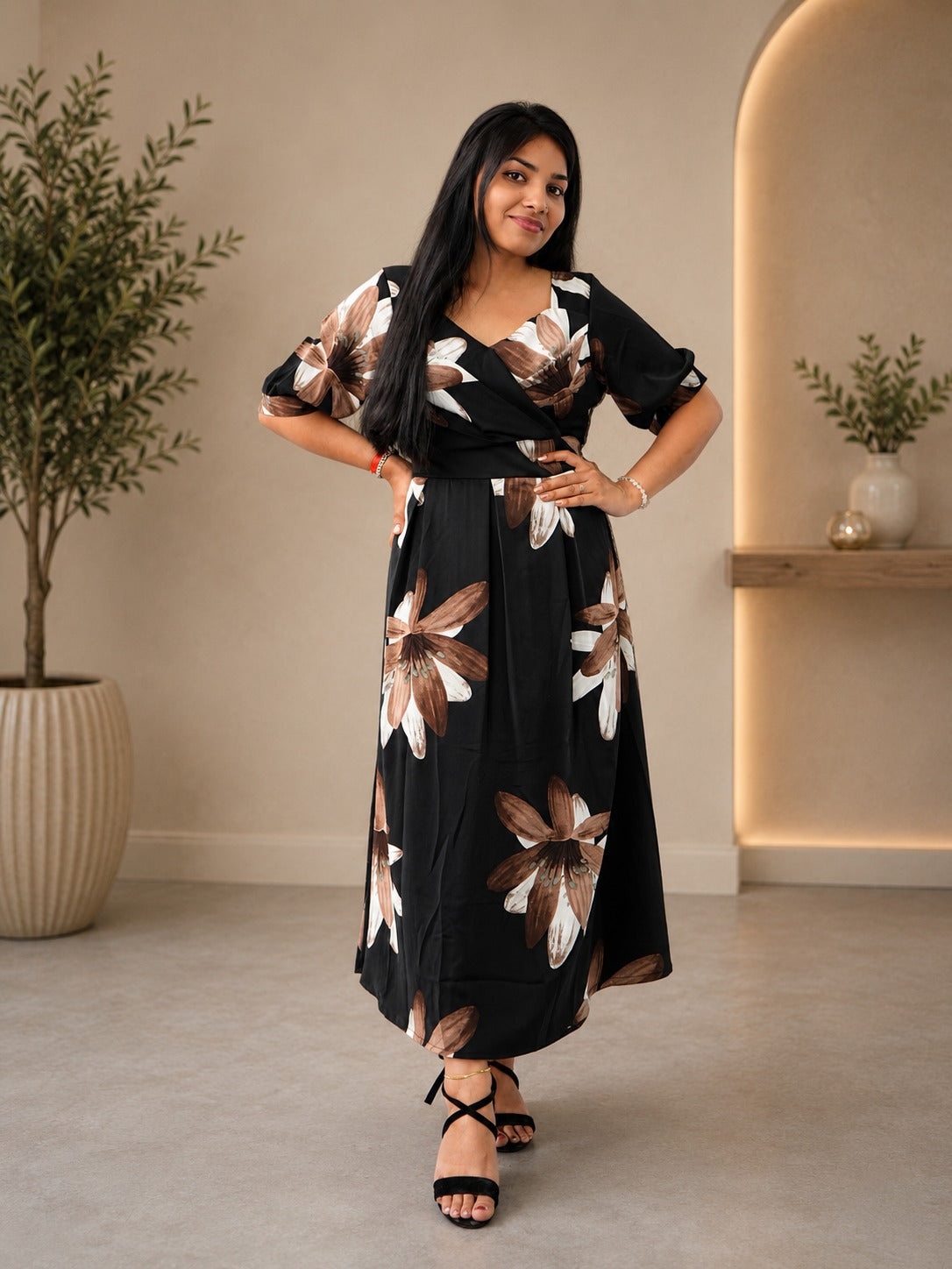 Woman wearing a black floral dress in an indoor setting with plants.